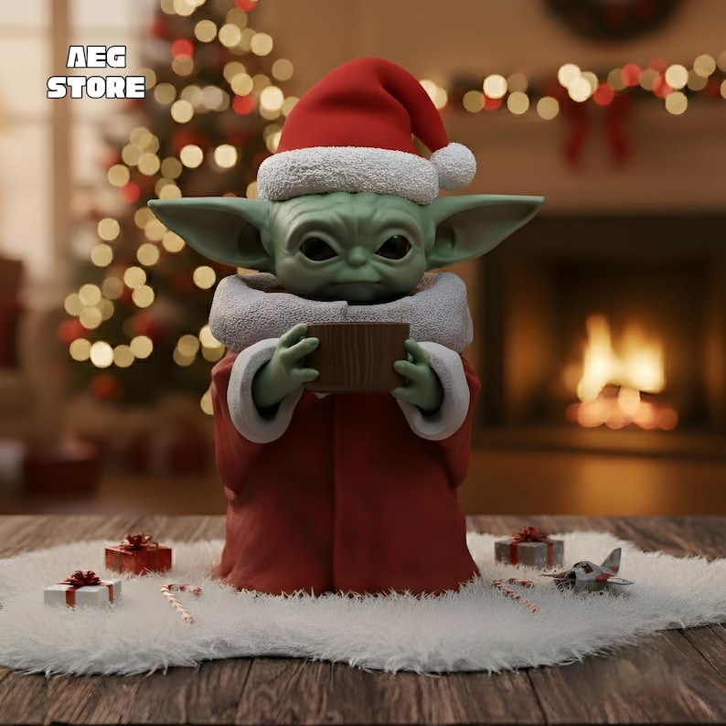 May include: A green creature figurine with large ears and dark eyes, wearing a red Santa hat with white trim and a matching red robe with a white collar. The figure holds a small brown rectangular object. Text AEG STORE appears in the corner.