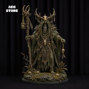 May include: A detailed figurine of a robed figure wearing a horned skull headdress, holding a staff with a hanging skull lantern and a separate skull ornament. The figure features textured green and brown garments, standing on a rocky base.