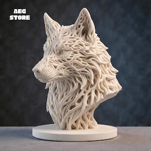 Puede incluir: Busto de lobo color crema con intrincados detalles calados. La cabeza del lobo se representa de perfil, montada sobre una base circular. El texto "AEG STORE" está en la esquina superior izquierda.