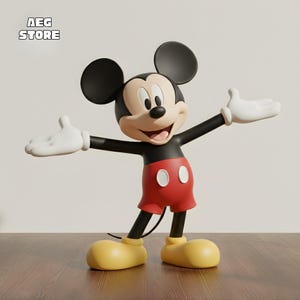 Könnte beinhalten: Eine 3D-gerenderte Mickey Mouse-Figur mit ausgestreckten Armen. Mickey trägt rote Shorts, gelbe Schuhe, weiße Handschuhe und hat schwarze Ohren. Die Figur steht auf einer Holzoberfläche. Der Text "AEG STORE" befindet sich oben links.