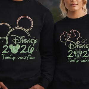 May include: Black sweatshirts with Disney-themed designs. One features Mickey Mouse ears, the text "Disney 2020 Family Vacation" in green glitter. The other has a Minnie Mouse bow and similar text. A fun matching set.