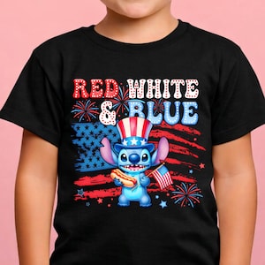 May include: Black t-shirt featuring a cartoon character holding a hot dog and a small American flag. The shirt has the words "RED WHITE & BLUE" in a patriotic design. The character is wearing a red, white, and blue hat.