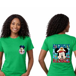 May include: A green t-shirt featuring Minnie Mouse. The front has a small Minnie Mouse graphic. The back of the shirt has a larger graphic of Minnie Mouse in a sailor hat with the words "MINNIE" in red and blue.