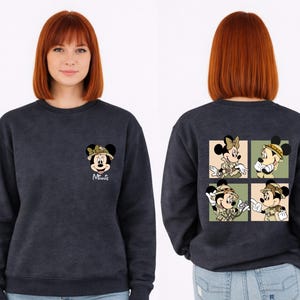 May include: Dark blue sweatshirt with Minnie Mouse in safari clothing. The front has a small Minnie Mouse graphic and the name "Minnie". The back shows a four-panel design of Minnie and Mickey Mouse in safari outfits.