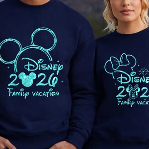 May include: Navy blue sweatshirts with a turquoise Disney design. One features Mickey Mouse ears, the other Minnie Mouse ears. Both say "Disney 2020 Family Vacation."