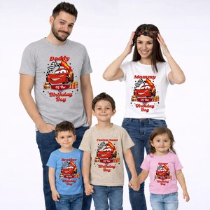 May include: Family matching t-shirts with a cartoon car design. The shirts are gray, white, blue, tan, and pink. Text on the shirts reads "Daddy", "Mommy", "Brother", "Sister", and "Custom Name" with "Of The Birthday Boy".