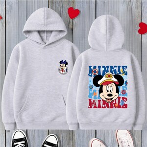 May include: Two light gray hoodies with a Minnie Mouse design. One has a small Minnie Mouse graphic on the front. The other has a larger Minnie Mouse graphic on the back with the words "Minnie" in blue and red.