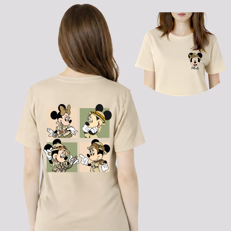 May include: A beige t-shirt with a cartoon design of Mickey and Minnie Mouse in safari outfits. The design is on the back of the shirt, with a smaller version of Minnie Mouse on the front. The shirt has short sleeves.