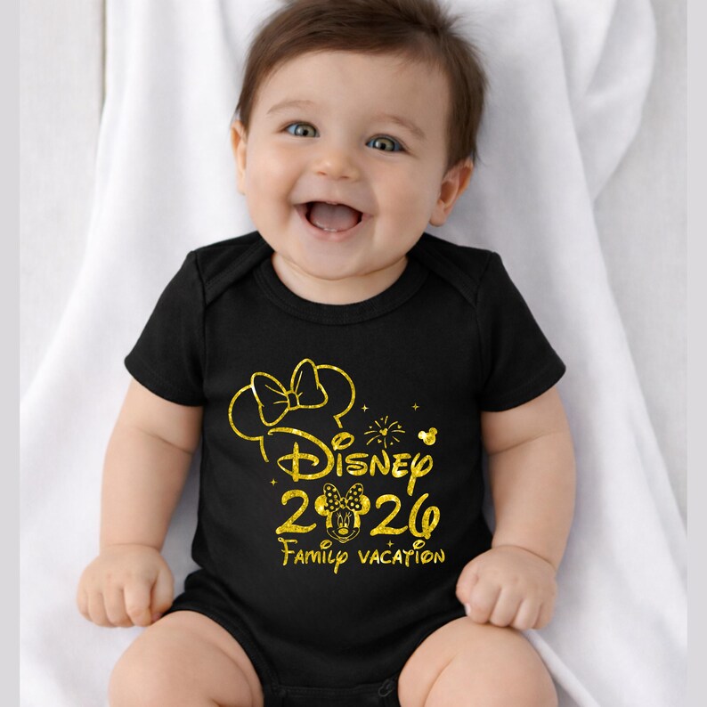 May include: A black baby bodysuit with a gold Minnie Mouse design. The design includes a bow, the word "Disney", the year "2020", and the words "Family Vacation". The baby is smiling and sitting on a white surface.