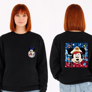 May include: Black sweatshirt featuring a Minnie Mouse graphic. The front has a small Minnie Mouse design, while the back displays a larger nautical-themed Minnie Mouse graphic with the text "Minnie".