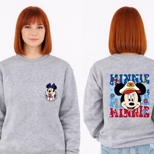 May include: A gray sweatshirt featuring Minnie Mouse. The front has a small Minnie Mouse graphic. The back displays a larger Minnie Mouse graphic with the word "MINNIE" in blue and red, surrounded by nautical elements.