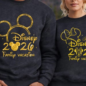 May include: Two dark gray sweatshirts with gold glitter designs. One features a Mickey Mouse head outline, the text "Disney 2020 Family Vacation". The other has a Minnie Mouse head outline, the same text, and a bow.