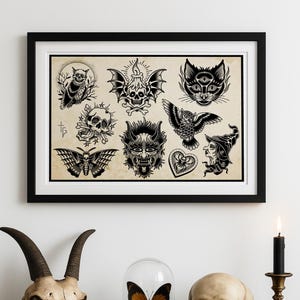 Könnte beinhalten: Ein gerahmter Druck mit verschiedenen Tattoo-Designs in Schwarz-Weiß, darunter Schädel, Eulen und ein Schmetterling, steht über einem dunklen Holzschrank. Der Schrank zeigt einen Ziegenschädel, menschliche Schädel und einen Schmetterling in einer Glasglocke, mit einer brennenden Kerze.