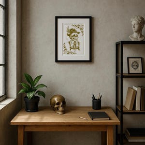 Puede incluir: Una impresi&oacute;n enmarcada de un esqueleto con sombrero y chaleco cuelga sobre un escritorio de madera. Una calavera de bronce, una planta en maceta y un cuaderno negro est&aacute;n sobre el escritorio. Una estanter&iacute;a de metal negro con libros y un busto es visible.