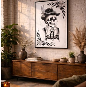Puede incluir: L&aacute;mina art&iacute;stica en blanco y negro enmarcada que representa una calavera con sombrero y tirantes, con motivos florales y de hojas. La obra de arte cuelga sobre un mueble de madera, adornado con jarrones, plantas y otros objetos decorativos.