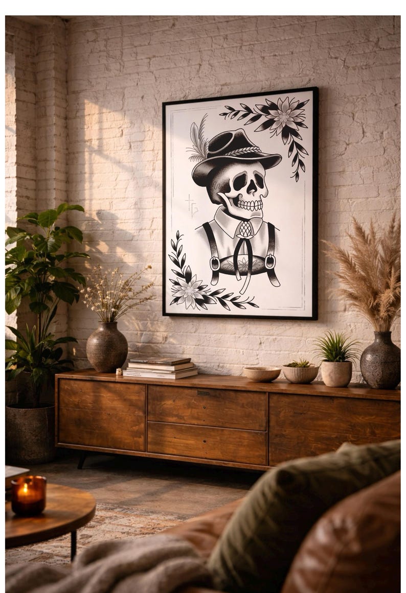 Puede incluir: L&aacute;mina art&iacute;stica en blanco y negro enmarcada que representa una calavera con sombrero y tirantes, con motivos florales y de hojas. La obra de arte cuelga sobre un mueble de madera, adornado con jarrones, plantas y otros objetos decorativos.