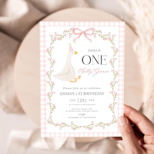 May include: A pink and white gingham patterned birthday invitation with floral and bow accents. The invitation features a cartoon goose wearing a party hat and the text "EMMA IS ONE Silly Goose". The invitation is for Emma's 1st birthday.