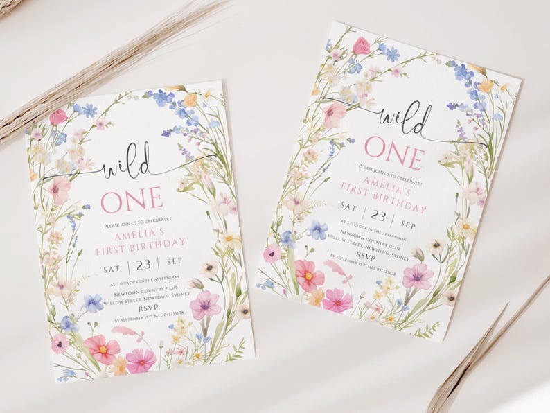 May include: Two floral-themed birthday invitations with the text "wild ONE" in a handwritten font. The invitations feature a watercolor floral border with pink, blue, and white flowers. The text includes the date, time, and location of the party.