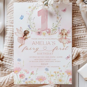 May include: A whimsical invitation for a first birthday party. The design features a large pink number 1, fairy illustrations, floral accents, and the text "Amelia's fairy first birthday". The invitation is on a white background.