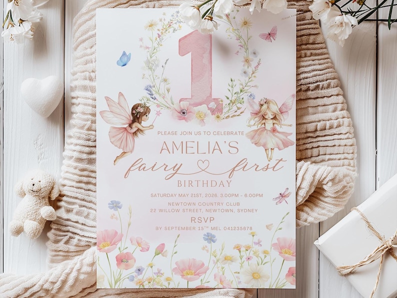 May include: A whimsical invitation for a first birthday party. The design features a large pink number 1, fairy illustrations, floral accents, and the text "Amelia's fairy first birthday". The invitation is on a white background.