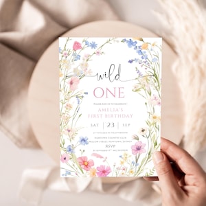 May include: A floral-themed birthday invitation with the words "wild ONE" in a script font. The invitation features a watercolor design of pink, blue, and yellow flowers. The text includes the name "Amelia", the date, and RSVP information.