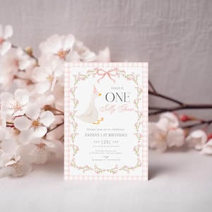 May include: A birthday invitation with a pink gingham border and floral accents. The invitation features a cartoon goose wearing a party hat and the text "Emma is One". The invitation is surrounded by white flowers.