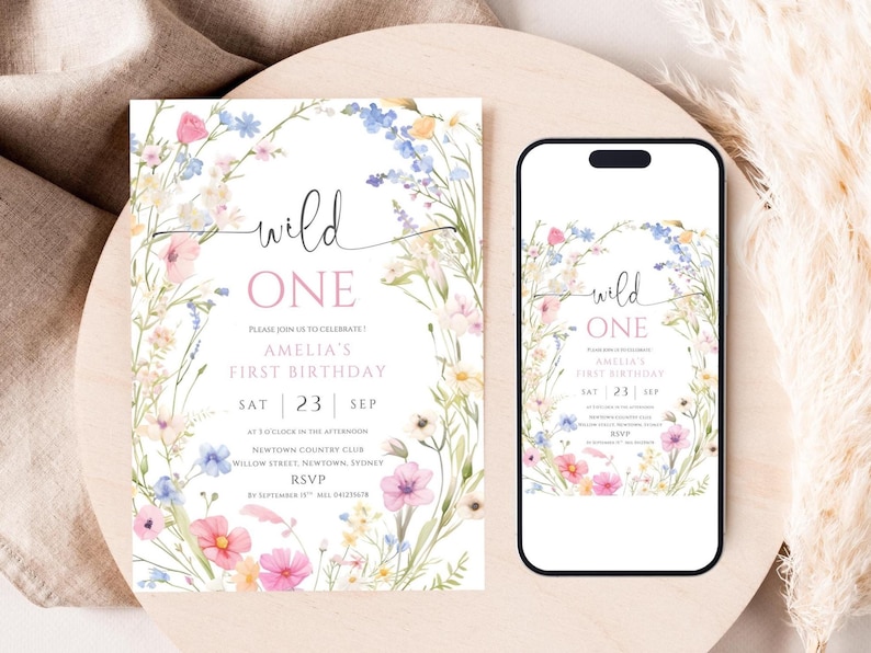 May include: A floral-themed invitation and a smartphone display, both featuring the text "wild ONE" and details for Amelia's first birthday. The design includes watercolor flowers in pink, blue, and yellow, with the date of September 23rd.