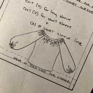 Op de afbeelding: Handgetekend patroon voor een boerenblouse met instructies voor het knippen en naaien. Het patroon bevat een vouwlijn voor het kanaal, een zoom en opties voor korte en lange mouwen.