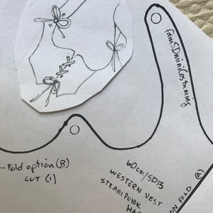May include: A black and white line drawing of a vest with a lace-up front and butterfly details. The drawing is on a white piece of paper with the text "60cm/SD13 Western Vest Steampunk Han" written below it.