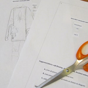 May include: A sewing pattern for a boy's cavalier cape with instructions for cutting and sewing. The pattern includes a front/back piece and two sleeves. The suggested fabrics are soft flowing, brushed cotton, or chamois.