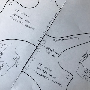 May include: A black and white line drawing of a vest pattern with the text "EID WOMAN WESTERN VEST STEAMPUNK HARNESS" and "CUT (1) on FOLD (A)" and "Pam SD mini Costuming" and "(8) optional fold line".