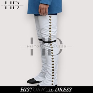 Op de afbeelding: Witte over-the-knee laarzen met goudkleurige knopen aan de zijkant. De laarzen hebben zwarte zolen en een zwarte band met een gesp. Ze maken deel uit van een historische jurkencollectie. De tekst "HISTORICAL DRESS" staat onderaan de afbeelding.