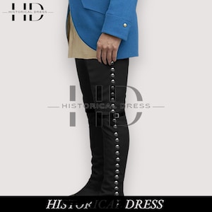May include: Black knee-high boots with silver-colored button detailing. The boots have a buckle closure and are worn with a blue coat. The image includes the text "HISTORICAL DRESS".
