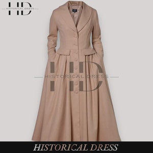 May include: A long, tan coat with a tailored silhouette. The coat features a notched collar, button closures, and pockets. The skirt portion is pleated, and the coat is labeled "HISTORICAL DRESS".