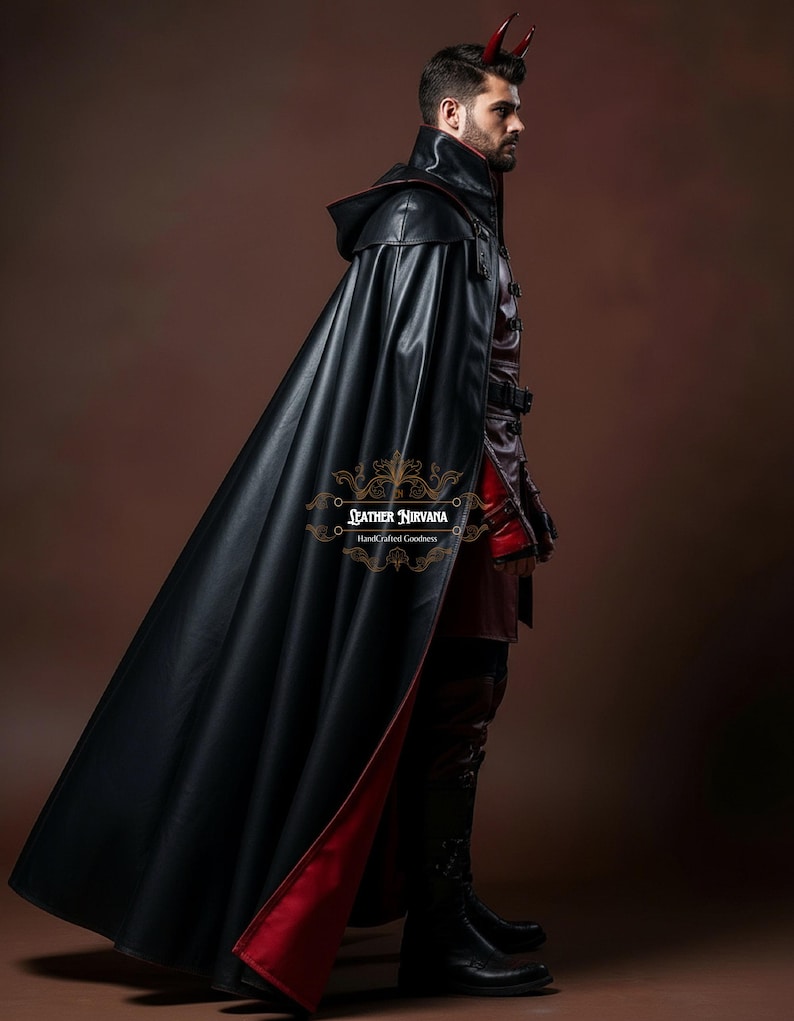 May include: A black leather cape with a red lining, worn over a matching outfit. The cape has a hood and is part of a costume. The image includes the text "Leather Nirvana Handcrafted Goodness".