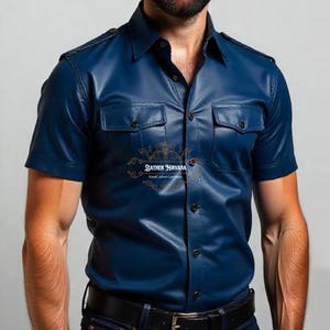 May include: A short-sleeved, navy blue leather shirt with two chest pockets and a button-down front. The shirt is paired with dark blue jeans and a black belt. The text "LEATHER NIRVANA Handcrafted Goods" is visible.