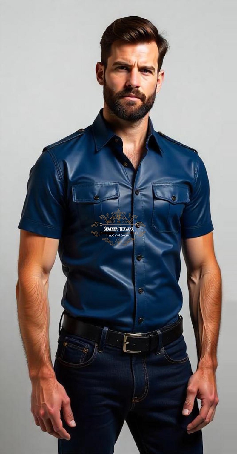 May include: A short-sleeved, navy blue leather shirt with two chest pockets and a button-down front. The shirt is paired with dark blue jeans and a black belt. The text "LEATHER NIRVANA Handcrafted Goods" is visible.