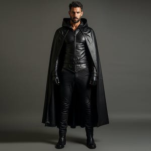 May include: A person wearing a black leather hooded cape, jacket, pants, gloves, and boots. The outfit is all black and appears to be made of leather. The person is standing in front of a gray background.