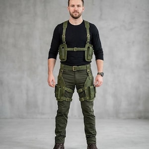 May include: An olive green leather chest harness and matching leg holster set featuring multiple pouches, adjustable straps, and brass-toned buckles. The harness secures over the torso, while the leg holsters attach to a belt and wrap around thighs.