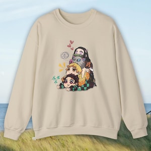 Peut inclure: Sweat-shirt beige avec un graphisme color&eacute; de personnages d'anime. L'illustration comprend trois personnages empil&eacute;s, avec des c&oelig;urs et des bulles de dialogue. Le sweat-shirt a un col rond et des manches longues.
