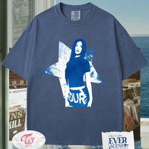 May include: Blue Comfort Colors t-shirt with a blue graphic of a woman inside a white star. The word "OUR" is printed on the bottom of the graphic. The shirt has a crew neck and short sleeves. The tag says XL-70-10.