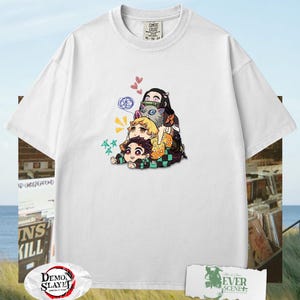 Peut inclure: T-shirt blanc avec un motif color&eacute; de personnages d'anime empil&eacute;s les uns sur les autres. Le design comprend des personnages avec diff&eacute;rentes couleurs de cheveux et tenues. Le t-shirt a un col rond et des manches courtes. Le logo "Demon Slayer" est visible.