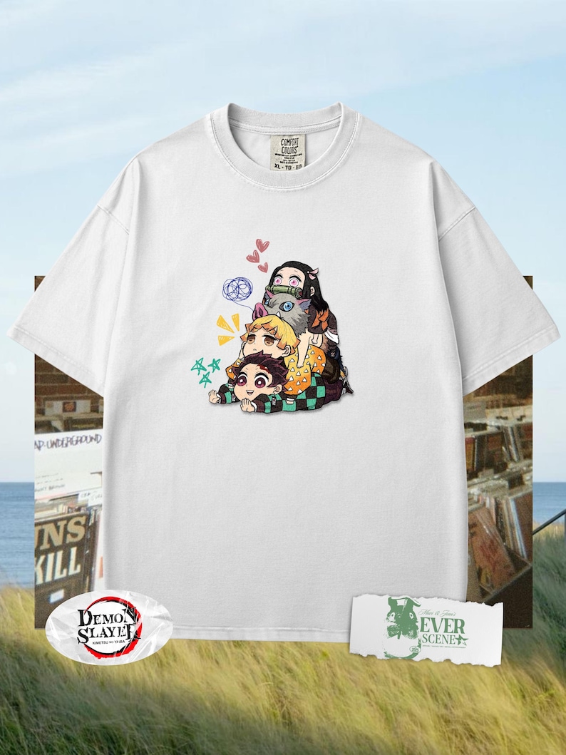 Peut inclure: T-shirt blanc avec un motif color&eacute; de personnages d'anime empil&eacute;s les uns sur les autres. Le design comprend des personnages avec diff&eacute;rentes couleurs de cheveux et tenues. Le t-shirt a un col rond et des manches courtes. Le logo "Demon Slayer" est visible.