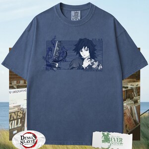 May include: A blue Comfort Colors t-shirt with a rectangular graphic of an anime character and the text "TOMIOKA GIYU". The shirt also features the "Demon Slayer" logo and the text "EVER SCENE".