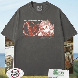 May include: Dark grey t-shirt with a graphic featuring a character illustration and Japanese text. The shirt includes the text "SET YOUR HEART ABLAZE" and "KYOJURO RENGOKU". The shirt is a Comfort Colors XL-TG.