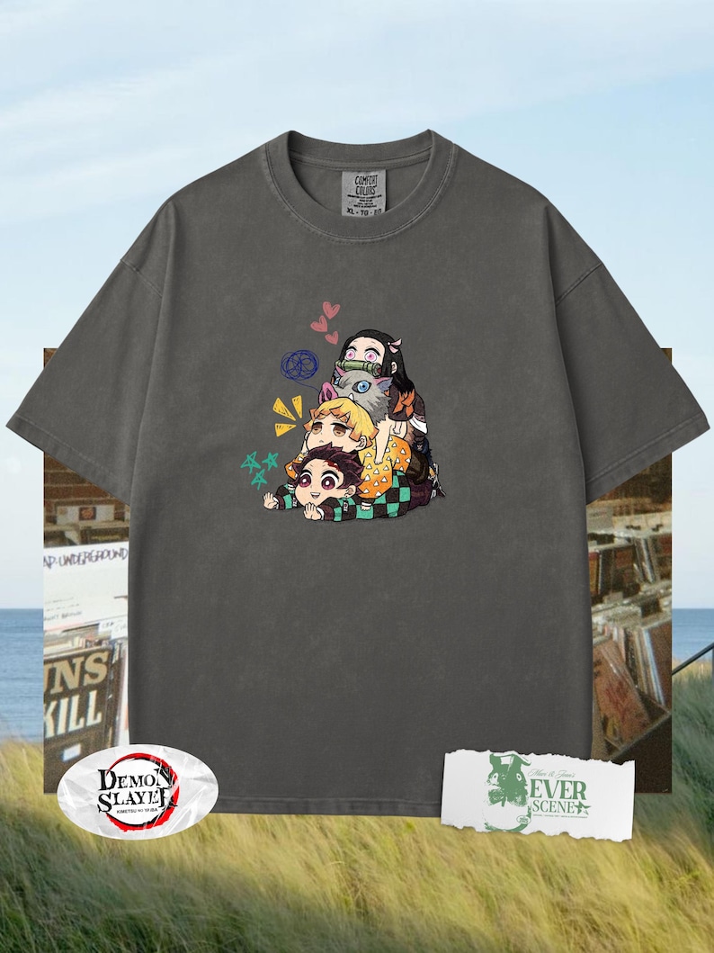 Peut inclure: T-shirt gris fonc&eacute; avec un motif de personnages d'anime empil&eacute;s. Le design pr&eacute;sente des personnages de dessins anim&eacute;s de diff&eacute;rentes couleurs. Le t-shirt a un col rond et des manches courtes. L'&eacute;tiquette indique "COMFORT COLORS".