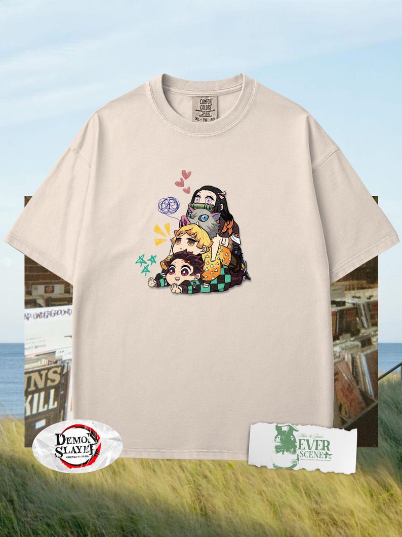 Peut inclure: T-shirt cr&egrave;me avec un graphisme de personnages d'anime empil&eacute;s les uns sur les autres. Le design comprend des c&oelig;urs, des &eacute;toiles et d'autres d&eacute;tails. Le t-shirt a un col rond et des manches courtes. Le texte "Demon Slayer" est visible sur un logo.