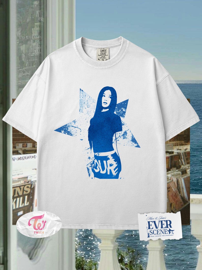 May include: White t-shirt featuring a blue graphic of a woman and the word "TOUR". The design is set against a starburst background. The shirt has a crew neck and short sleeves. The tag on the shirt reads "COMFORT COLORS".