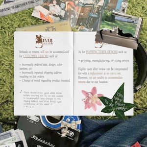 Peut inclure: Un collage d'objets sur une surface verte, dont un lecteur CD, un magazine et une page imprim&eacute;e avec du texte sur les retours. Il y a aussi des photos, une fleur et une feuille avec le texte "You have a right to be happy".
