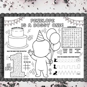 May include: Black and white birthday placemat with the text "PENELOPE IS A BOSSY ONE!". Features a cake, baby with balloons, word search, maze, and other activities. Includes the number "1" and the words "Decorate the Cake".